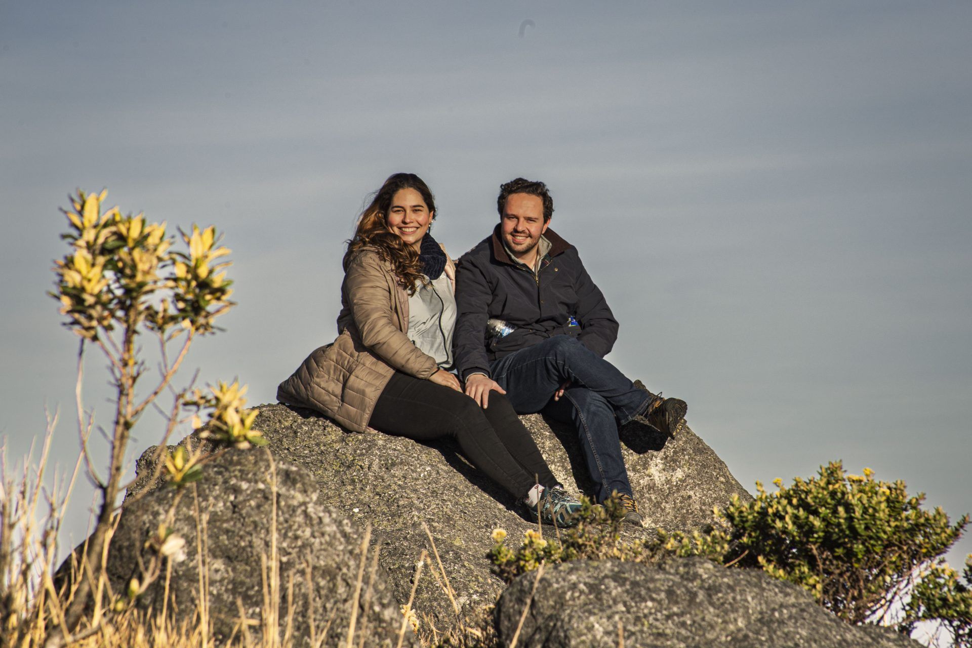 Two visitors sitting among flowering frailejones in the páramo near the Neusa reservoir